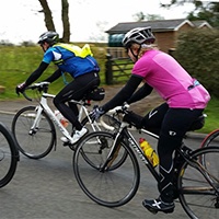 Two cyclists ride along a road