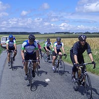 a group of cyclists ride along a road
